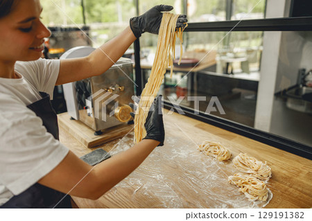 Enjoy the delightful experience of freshly made pasta being stretched in a modern kitchen setting Enjoy the delightful experience of freshly made pasta being stretched in a modern kitchen setting 129191382