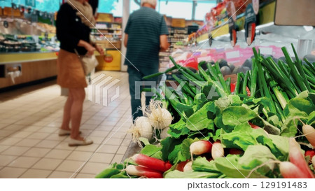 A senior French couple is buying vegetables at the supermarket 129191483