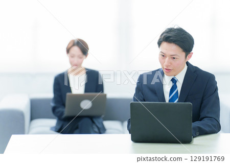 Business people working at desks in a free address system 129191769