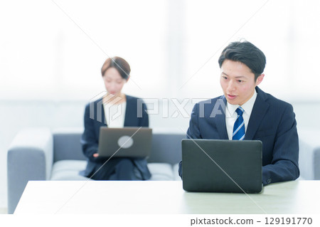 Business people working at desks in a free address system 129191770