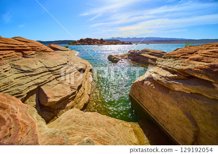 Red Sandstone Rocks and Lake Water with Distant Mountains Eye Level Perspective Red Sandstone Rocks and Lake Water with Distant Mountains Eye Level Perspective 129192054