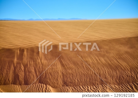 Golden Sand Dune Ripples with Distant Mountains and Blue Sky Eye Level 129192185