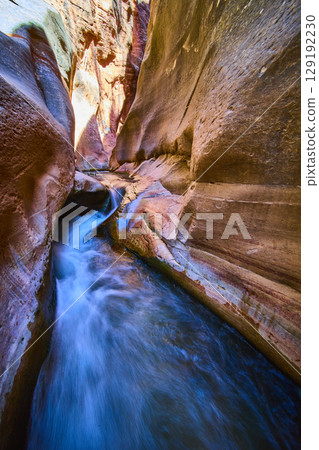 Slot Canyon Waterfall and Flowing Stream with Sunlit Sandstone Low Angle View 129192230