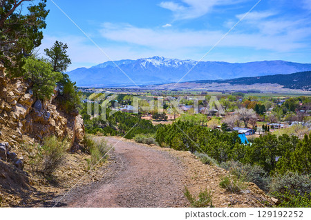 Rugged Desert Path Snow Capped Mountains and Green Valley Community Elevated View 129192252