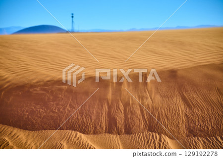 Wind Sculpted Sand Dunes with Distant Hill and Tower Eye Level Perspective 129192278