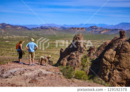 Hikers and Dog Exploring Rocky Desert Outcrop with Vast Valley Eye Level 129192378