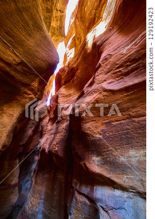 Sandstone Slot Canyon Walls with Flowing Lines and Sunlit Sky Upward View 129192423