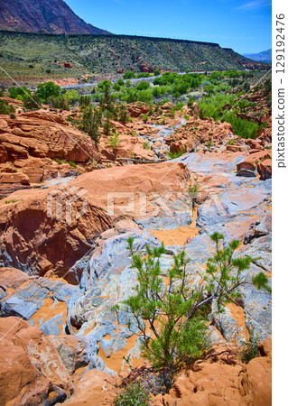 Red Sandstone Formations Blue Mineral Veins and Desert Shrub Eye Level View 129192476