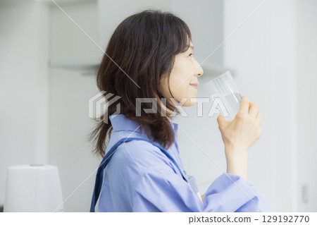 Woman drinking water in the kitchen 129192770