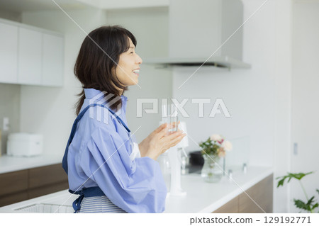 Woman drinking water in the kitchen 129192771