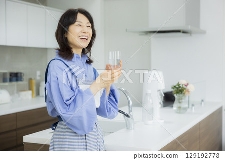 Woman drinking water in the kitchen Woman drinking water in the kitchen 129192778