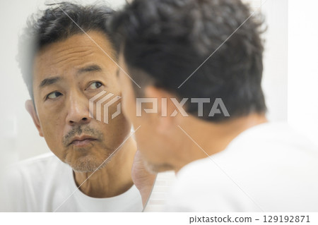 Middle-aged man looking in the mirror 129192871