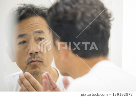 Middle-aged man looking in the mirror 129192872