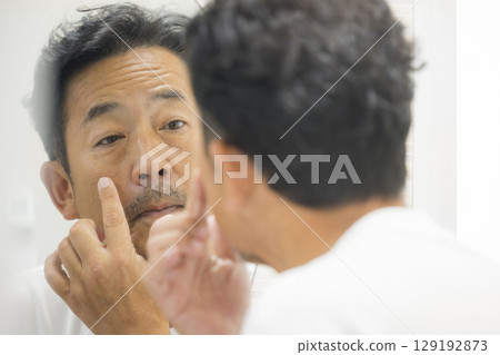 Middle-aged man looking in the mirror 129192873