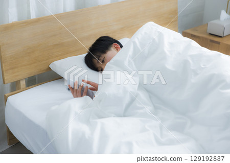 Young man using smartphone in bed 129192887