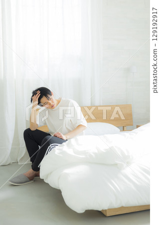 坐在床上的一個年輕人 坐在床上的一個年輕人 129192917
