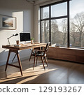 A laptop computer sits on a desk in an office with natural morning light 129193267
