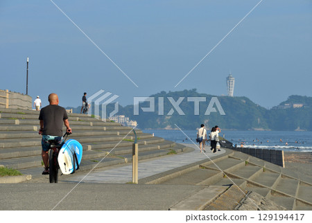 沿著 Kugenuma 海濱長廊騎自行車的衝浪者 129194417