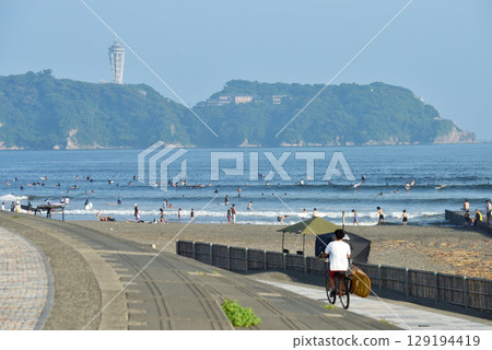 沿著 Kugenuma 海濱長廊騎自行車的衝浪者 沿著 Kugenuma 海濱長廊騎自行車的衝浪者 129194419