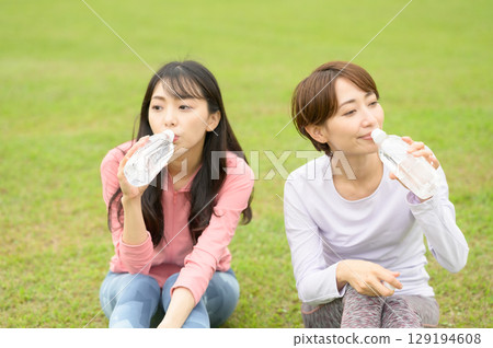 Two women taking a break after exercise and hydrating 129194608