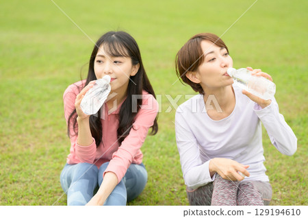 Two women taking a break after exercise and hydrating 129194610
