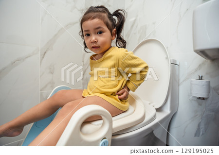 toddler girl is sitting on toilet at home. potty training and learning 129195025