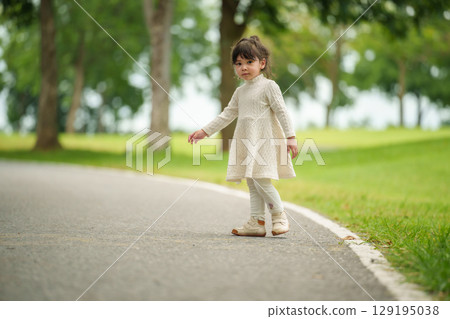 happy toddler girl standing on a pathway in park happy toddler girl standing on a pathway in park 129195038