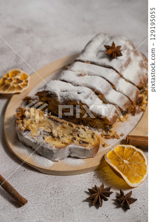 Slices of Homemade Christmas traditional cake pie with marzipan nuts and dried fruits pastry dessert stollen. Winter holidays season atmosphere. Delicious tasty composition home table setting 129195055