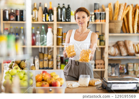 Adult woman seller offering corn flakes in grocery 129195569