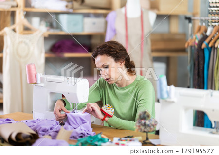 Woman tailor at work in cloth design shop Woman tailor at work in cloth design shop 129195577