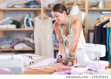 Woman seamstress work with scissors and cutting 129195618
