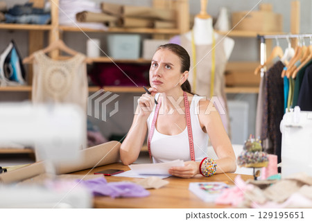 female dressmaker deals with documents in the atelier 129195651