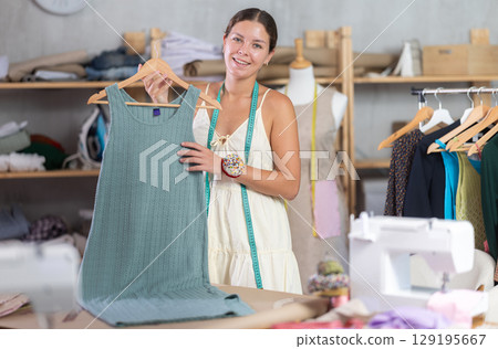 dressmaker presents a ready-made dress in a workshop dressmaker presents a ready-made dress in a workshop 129195667