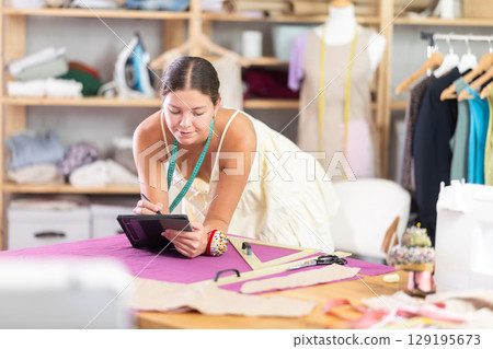 Woman dressmaker drawing on tablet 129195673