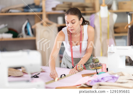 dressmaker marks and cuts the fabric 129195681