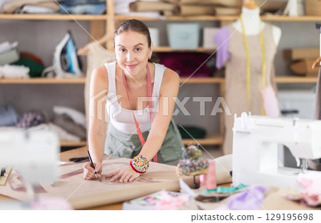 Woman dressmaker draws patterns using curved rulers 129195698