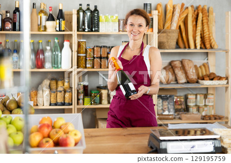 Adult woman seller offers wine in grocery store Adult woman seller offers wine in grocery store 129195759