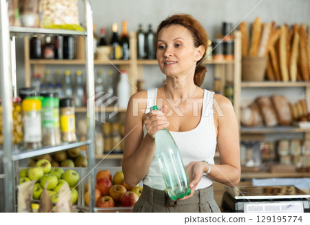 Adult female buyer choosing water in grocery store 129195774