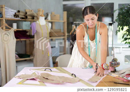 dressmaker marks and cuts the fabric dressmaker marks and cuts the fabric 129195821