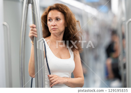 Adult woman stands in subway car Adult woman stands in subway car 129195835