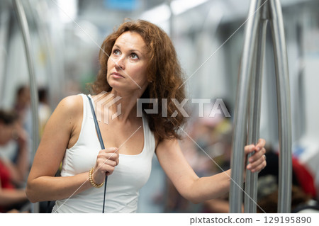 Adult woman stands in subway car 129195890