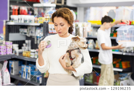 Buyers woman with Yorkshire Terrier choose healthy food and nutrition for pet in tin can Buyers woman with Yorkshire Terrier choose healthy food and nutrition for pet in tin can 129196235