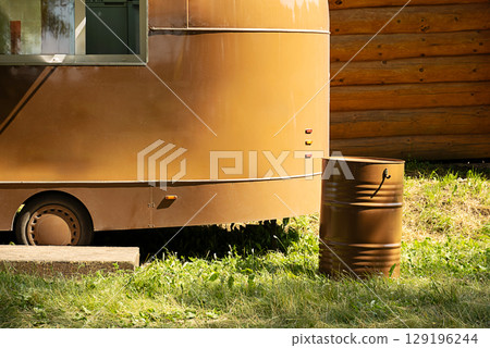 Mobile food truck parked next to a wooden wall with a barrel on grass. 129196244