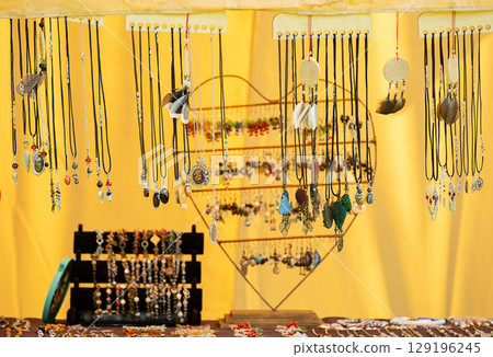 Handcrafted necklaces and earrings displayed at a market stall. 129196245