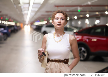 Adult woman stands in parking lot with keys Adult woman stands in parking lot with keys 129196305