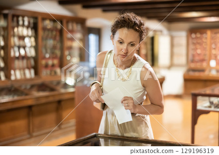 Woman looking at exhibits in glazed stands in museum Woman looking at exhibits in glazed stands in museum 129196319