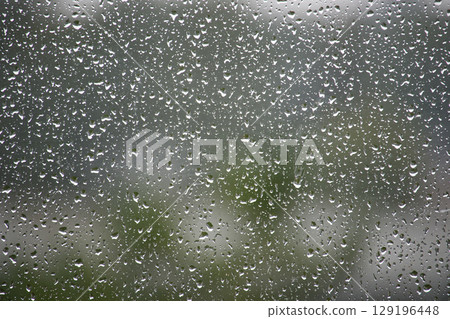 Raindrops on Glass Window with Natural Blurred Background Outdoors Raindrops on Glass Window with Natural Blurred Background Outdoors 129196448