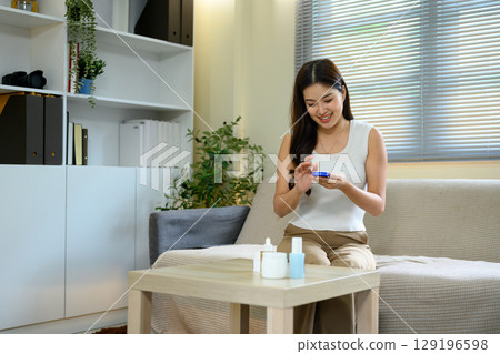 Smiling woman preparing to apply body lotion in a living room. Beauty and self care concept Smiling woman preparing to apply body lotion in a living room. Beauty and self care concept 129196598