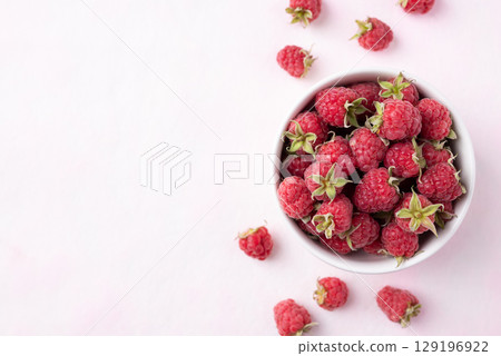 Top view of fresh ripe raspberry with leaf in bowl on pink background, Summer fruit 129196922