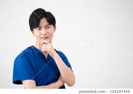 A young man wearing medical scrubs 129197449